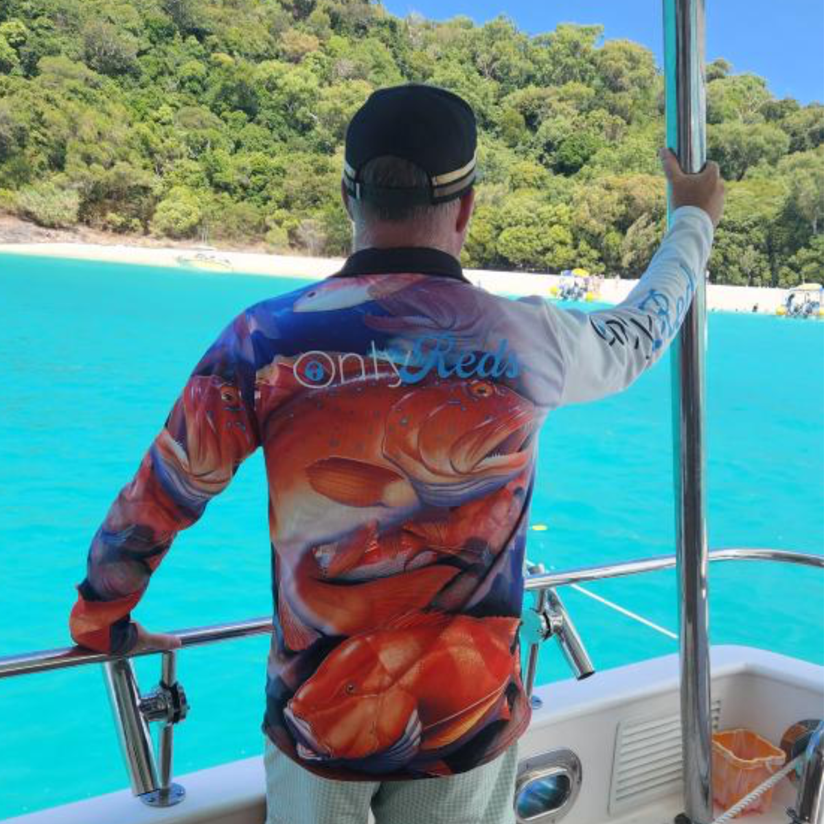 Person wearing The Dirty Oars Only Reds Mens Fishing Shirt on a boat in clear blue water.