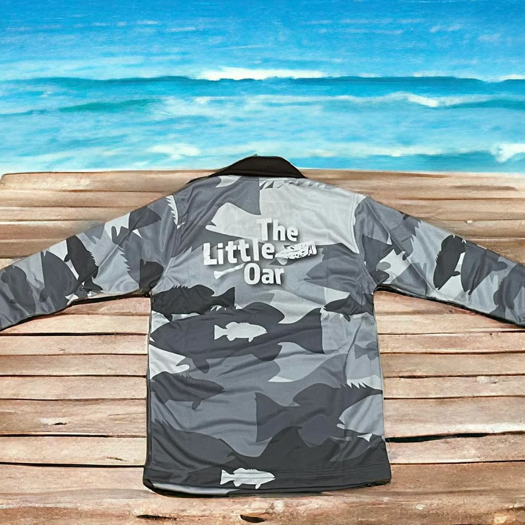 The Dirty Oar Coral Trout Kids Fishing Shirt, on wooden background.