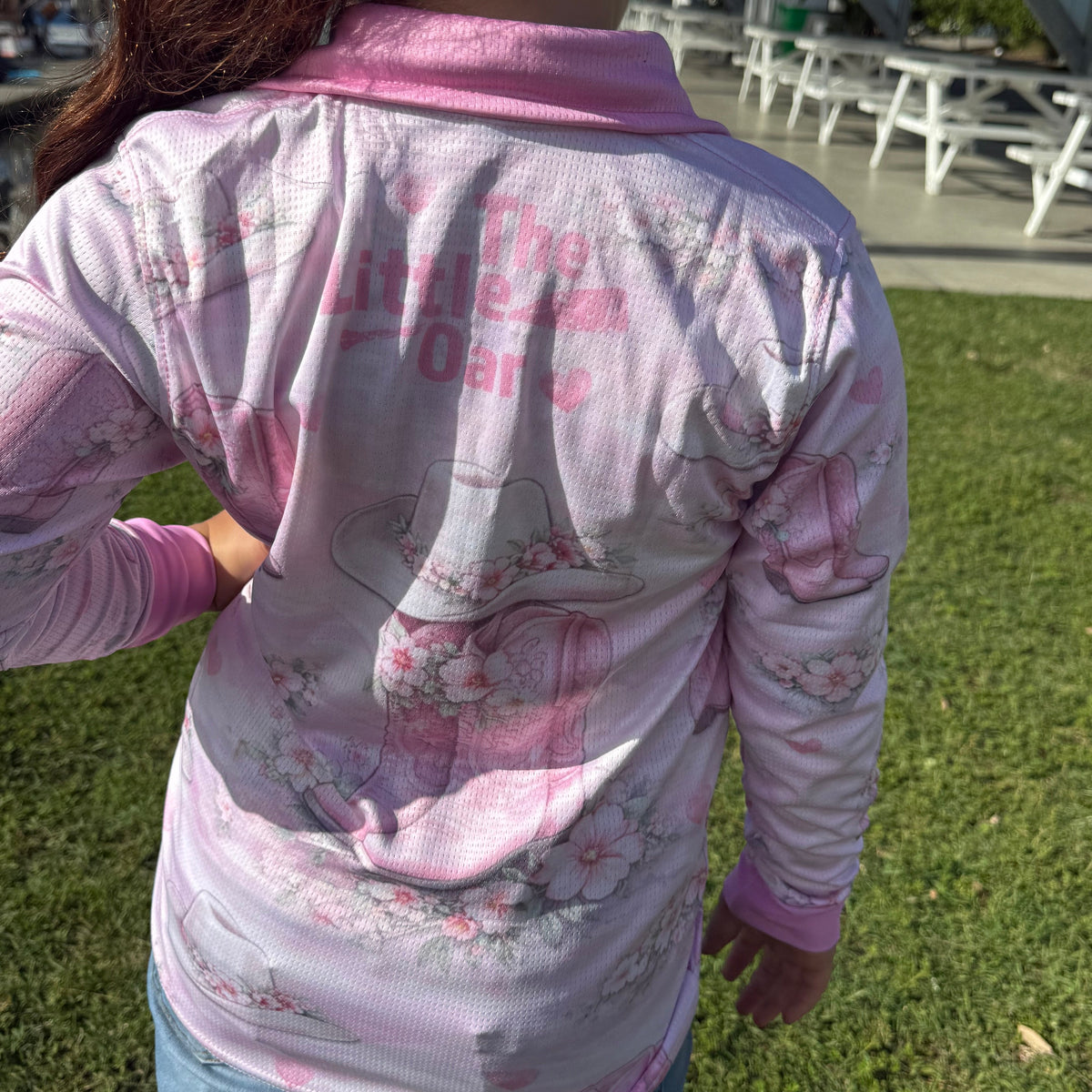Child wearing a The Dirty Oar Country Dreams Kids Fishing Shirt with text and graphics outdoors
