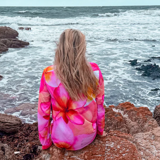 A person sitting on a rocky beach wearing a Frangipani Womens Fishing Shirt
