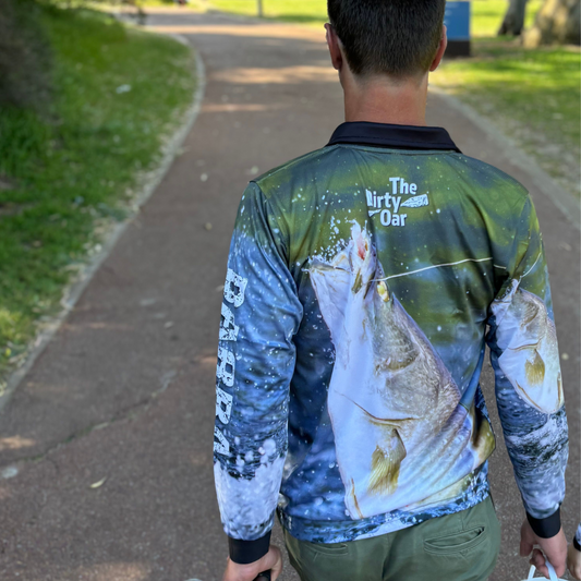 A person viewed from behind wearing the Dirty Oar Barra Mens Fishing Shirt, walking along a footpath.