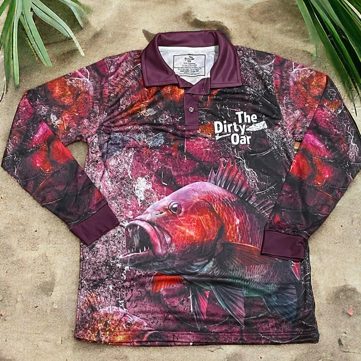 The Dirty Oar Mangrove Jack Mens Fishing Shirt on sandy background with plams.