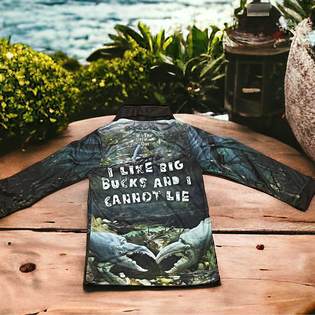 The Dirty Oars Mud Crab Kids Fishing Shirt on a wooden background with some flowers.