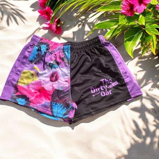 The Dirty Oar Princess womens shorts , on a sandy background with hibiscus and green leaves.