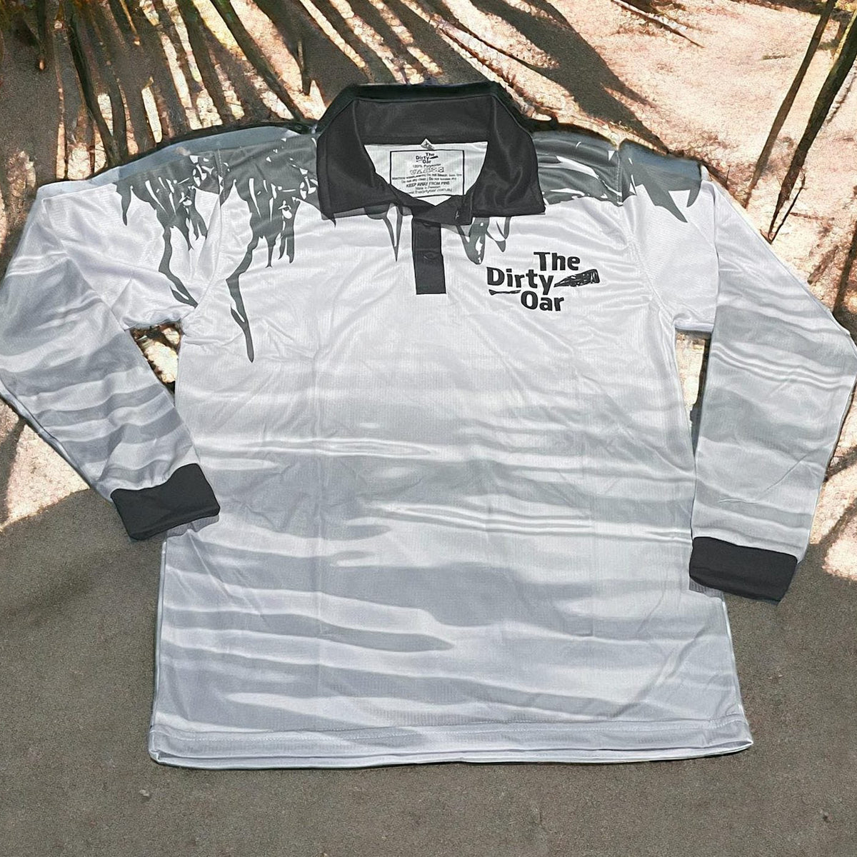 The Dirty Oar Mens Fishing Shirt White on sandy back ground with plams.